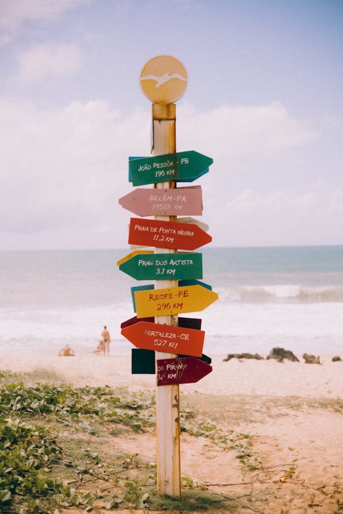 Wooden Direction Sign on Wooden Post by Sandy Beach